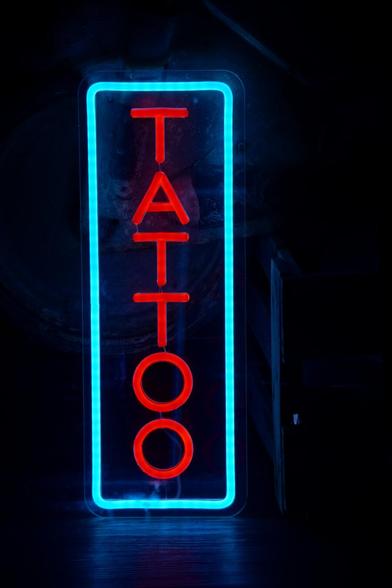 The picture shows a neon sign with a blue border and the word Tattoo spelled in red letters.