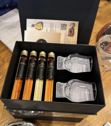 A velvet lined box with four “test tubes” of different rums and two glasses.
