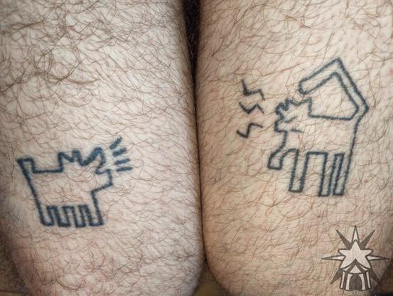 Tattoos: Black lineart of a Keith Haring dog [left] and cat [right, my original art] facing one another on each of my thighs. The way the stylized lines are extending from their open mouths, it appears as though they're talking to each other.