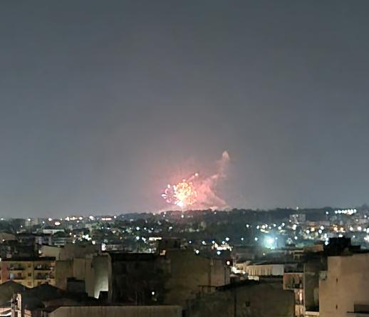 Fuochi d'artificio in lontananza, sotto un cielo notturno poco limpido