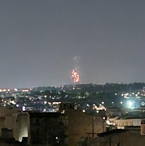 Fuochi d'artificio in lontananza, sotto un cielo notturno poco limpido
