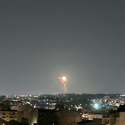 Fuochi d'artificio in lontananza, sotto un cielo notturno poco limpido