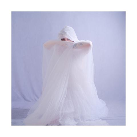 Portrait of a female model wrapped in white fabric in an ethereal look