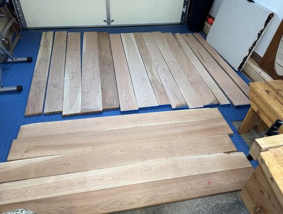 60 board feet of cherry wood layed out on garage floor