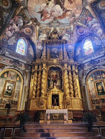 At center, altar and large altarpiece; the latter is about 25ft tall, has three Rococo columns on each side with two statues inset in the center, and is painted entirely in gold. Surrounding these are the Rococo molding and frescoes typical of this church.