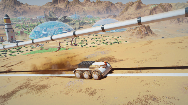 Surviving Mars screenshot shows an unmanned vehicle driving up an incline beside an industrial pipeline. Transparent blue domes and rocket ships can be seen standing in the red desert surrounded by mountains in background.