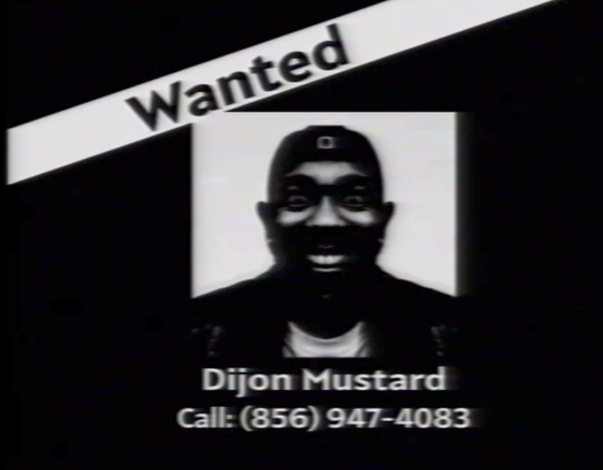 A wanted slide from an old VHS recording that says wanted in the upper right hand corner with a edited picture of Kendrick Lamar with text under it that says "Dijon Mustard, Call: (856) 947-4083".
