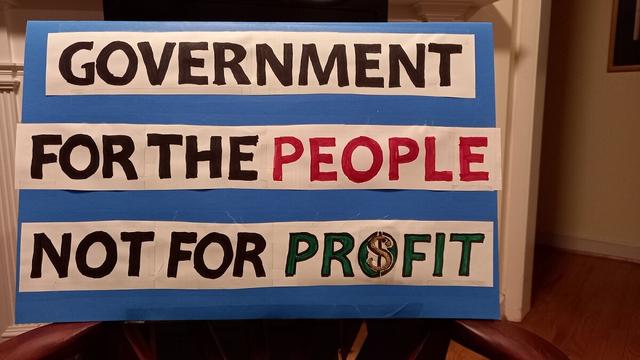 Protest sign that says "Government for the people, not for profit"
Blue posterboard and white strips of colored in letters. People is in red, Profit is in green and there's a glittery dollar sign in the O. DIY aesthetic, not quite punk though