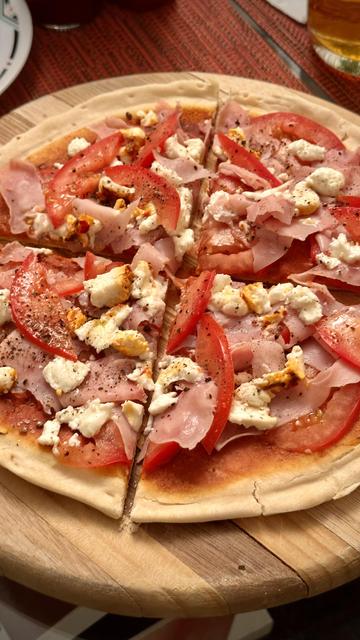 Fotografía de una pizza de jamón, tomate y queso de cabra hecha en casa.