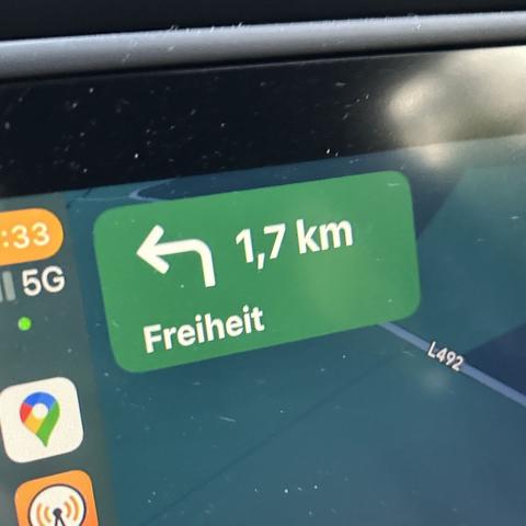 Ein Navigationsbildschirm zeigt eine Richtungsanweisung: In 1,7 km links abbiegen Richtung »Freiheit«. Auf der linken Seite sind Teile der Benutzeroberfläche mit dem Google-Maps-Symbol, Overcast-Symbol, Mobilfunksignal (5G) und Uhrzeit zu sehen. Die Straße im Hintergrund ist als L492 markiert.