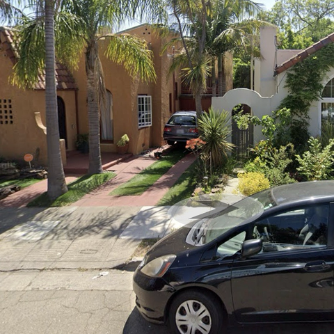 Screenshot from Google Maps Street View of my house, a yellow stucco California Spanish storybook-style bungalow, with my blue 2003 BMW 5-series station wagon on the driveway, raised up on QuickJack portable lifts during my engine swap project.
