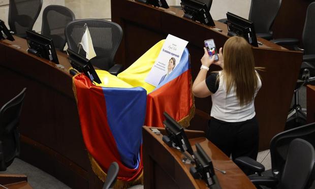 Una mujer toma una foto del escaño vacío del senador Miguel Uribe Turbay, con la bandera de Colombia y un mensaje de ánimo, el 9 de junio de 2025, en Bogotá. (Mauricio Dueñas Castañeda / EFE)