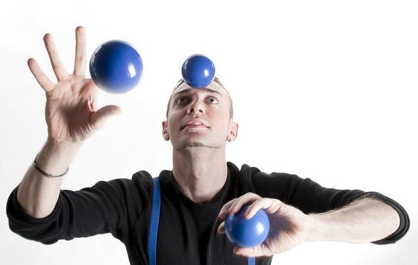 Une personne jongle avec trois balles bleues