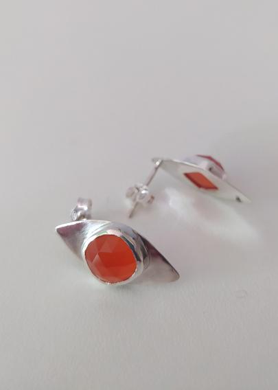 a pair of silver romboid stud earrings with an orange gemstone each