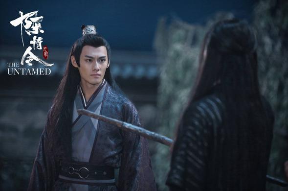 Jiang Cheng glares at Wen Ning as the other man, who is shown from behind, holds out the sheathed sword Suibian.