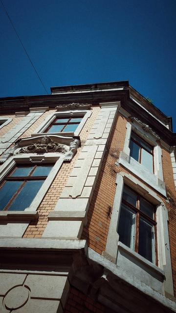An old houses facade in front of blue sky.