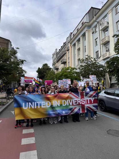 A small pride march with people holding a banner that says, "united in Diversity"