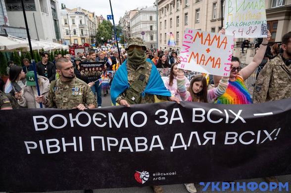 A pride parade with Ukrainian soldiers holding a banner in Ukrainian "воюємо за всіх - рівні права для всіх!", which translates as We fight for equal rights for all.