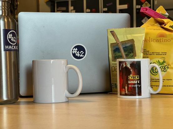 Mugs with 'bombilla' straws, packs of Maté tea, a laptop with a hack42 sticker