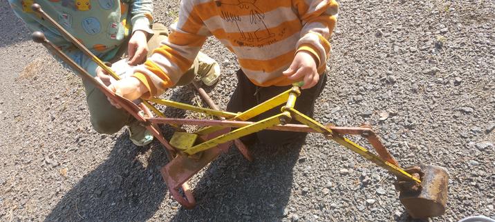 Small boys sanding an old toy excavator.