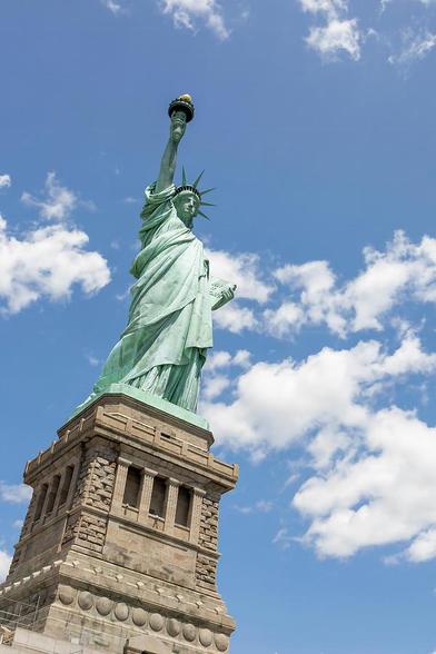 The iconic Statue of Liberty rises majestically at the entrance of the Hudson River, against the canvas of a brilliant blue sky. This symbol of freedom and hope stands unwaveringly on Liberty Island, a beacon of inspiration to all who lay eyes upon her.