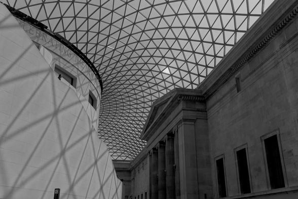 Central rotunda in the British Museum with a focus on the ceiling made out of triangles and their shadows. One clear tile looks much brighter in the monochrome photo.
