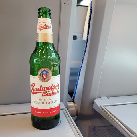 Foto einer fast ausgetrunkenen Flasche Bier der Marke Budweiser, in Tschechien gebraut, die auf einem Ausklapptischchen in der Bahn steht.