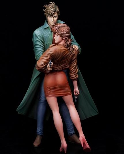 This image presents an intricately sculpted figure of two characters, rich with emotional tension and striking visual contrasts. The man, with windswept hair and piercing eyes, exudes calm confidence. Dressed in a flowing green trench coat over casual jeans and boots, his stance and subtle smirk suggest a figure of authority or mystery. His arm wraps protectively around the woman, reinforcing his role as a protector or ally. Their body language and expressions evoke an air of suspense, romance, and danger.
