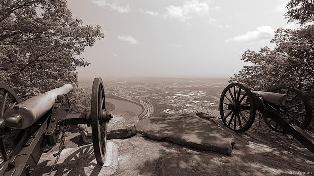 Chattanooga, TN seen from atop Lookout Mountain. Two Civil War cannons are in the foreground, one on the left and the other on the right. The image is sepia tone
