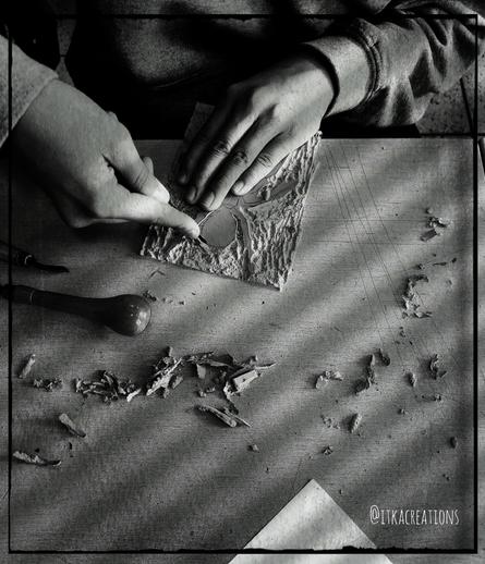 Découverte ici de la linogravure avec une classe de 6eme. Photo noir et blanc montrant deux petites mains s'affairant à la découpe d'une plaque à l'aide d'une gouge.