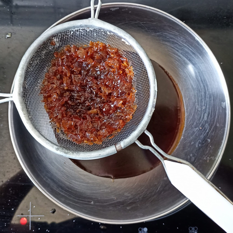 eine Metallschüssel, darauf ein Sieb. In der Schüssel die Sauce, im Sieb die Zwiebeln