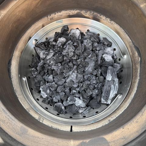 The inside of the Big Green Egg, showing the new fire bowl filled with charcoal.