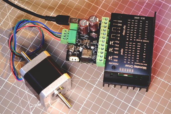 A top down photo of the whole project with a USB cable plugged in. The pcb is plugged into a black box that says Microstep Driver. A stepper motor is plugged into the pcb to the left