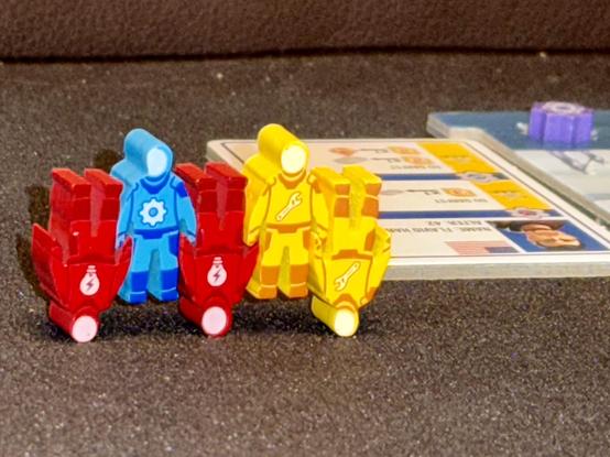 Foto von blauen, gelben und roten Meeples von "Mondbasis Shackleton", die "ineinander verkeilt" stehe und so aussehen, als würden sie eine artistisch aufführen