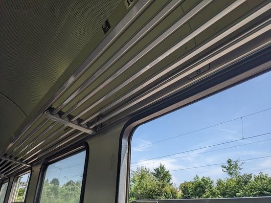 Foto eines offenen Fensters und der Gepäckablage in einem TRI-Zug.