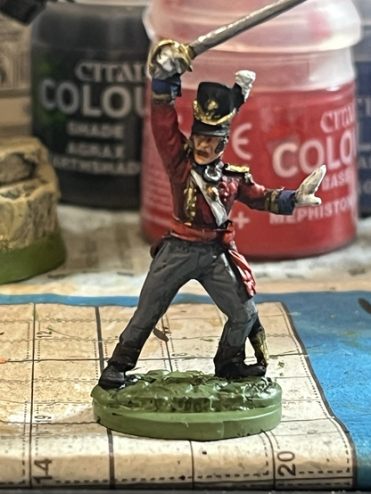 A British officer from the Napoleonic war era. He is brandishing a sword.