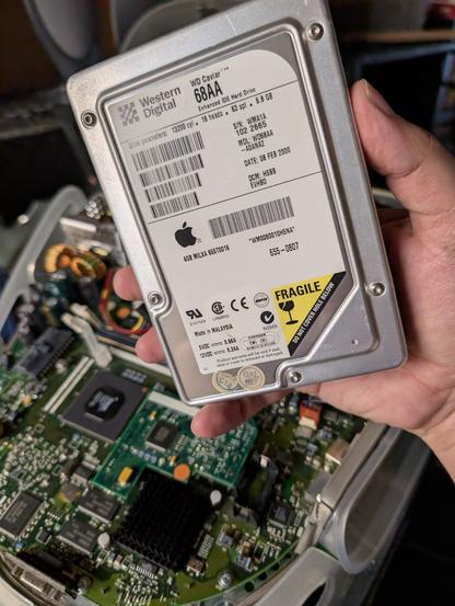 An opened iMac G3 with its removed 6GB Western Digital Caviar drive removed

The battery is also removed.