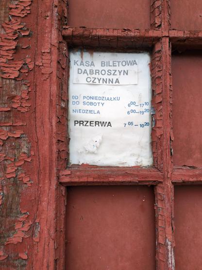 Zbliżenie na drzwi. W miejscu jednej z płyt umieszczono kartkę z wyklejonym komunikatem:

"""
Kasa biletowa Dąbroszyn czynna

od poniedziałku do soboty 6:00 – 17:10
niedziela 6:00 – 19:20
przerwa 7:05 – 10:20
"""