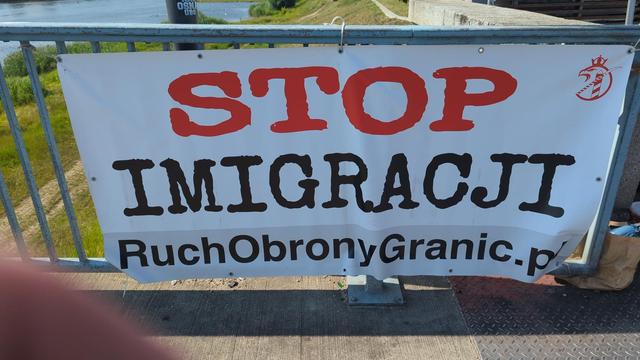 auf der polnischen Seite an der Grenze sassen auf beiden Straßenseiten mehrere Personen in markanter Kleidung. daneben eine große Plane am Brückengeländer
STOP 
IMIGRACJI
RubonObronxGranic.pl

ruft man die site auf, schlägt einem der Text aus dem Tröt entgegen.