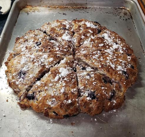 A sheet pan with freshly baked scones topped with powdered sugar.