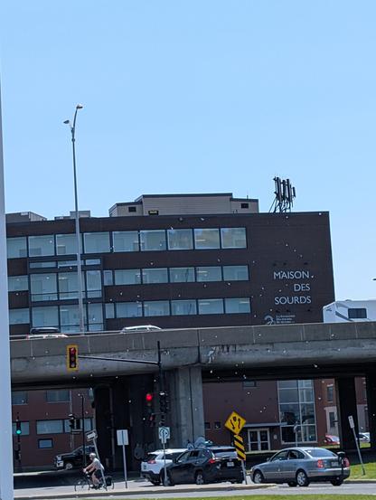 A photo of an highway viaduct. in the background a large building with the lettering "MAISON DES SOURDS"  (english: House of the Deaf) is abutting it.