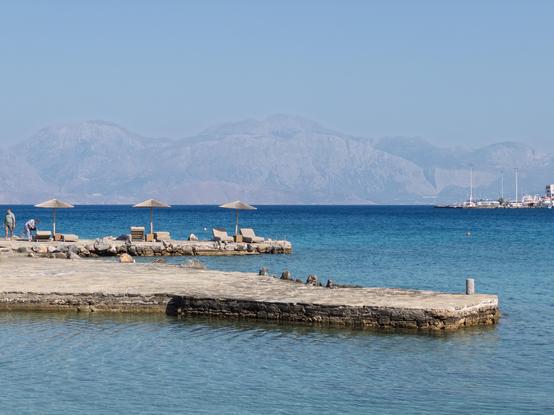 Seaside view with sun loungers and umbrellas on a pier at Minos Beach Art Hotel, Crete.