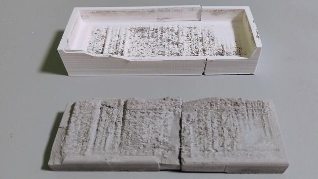 A broken slab of concrete with detailed FFT structures in, with its respective mould behind it. The mould has clearly been violently removed