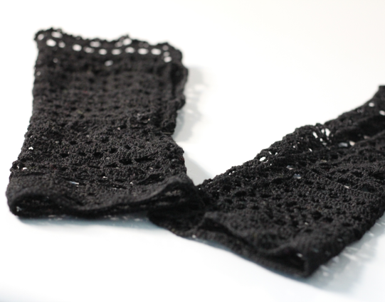 A pair of black wrist warmers made in crocheted cotton lace