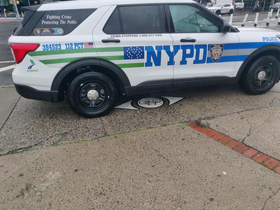 An NYPD SUV parked on a sidewalk. It says "fighting crime. Protecting the public." (lol)

Underneath the car is a wayfinding bike dot, showing where the bike lane is supposed to transition at the intersection. Except you can't bike there, because some asshole cops decided to park there instead.
