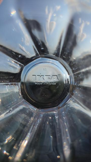 A photo of the inside of a glass beaker with the imprinted 'IKEA Made in France' branding at the bottom of the glass. The glass is being held horizontal to the horizon during sunset with the fading sunlight bouncing off and through the nine sides of the glass like a kaleidescope.