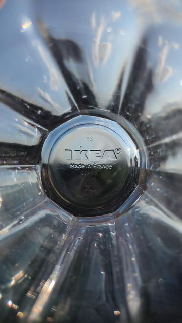 A photo of the inside of a glass beaker with the imprinted 'IKEA Made in France' branding at the bottom of the glass. The glass is being held horizontal to the horizon during sunset with the fading sunlight bouncing off and through the nine sides of the glass like a kaleidescope.