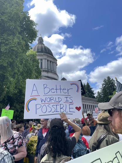 A sign reading “a better world is possible” in front of the Capitol.