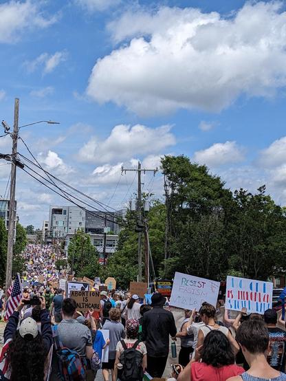 Photo from the perspective of somebody in a march with people filling the street as far as the eye can see which is about six blocks ahead