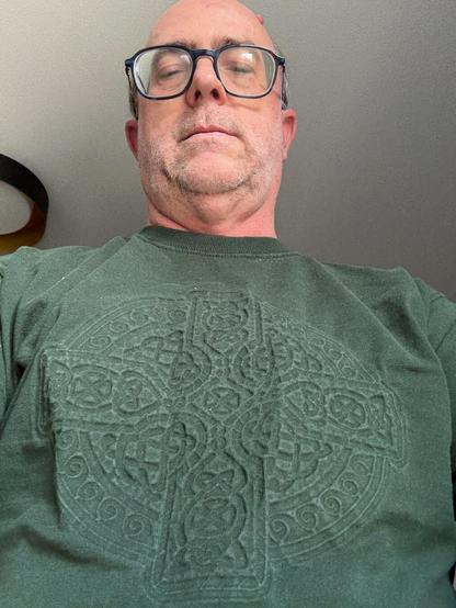 A middle aged white guy in glasses (i.e. me) in a green T-shirt embossed with a Celtic Cross.